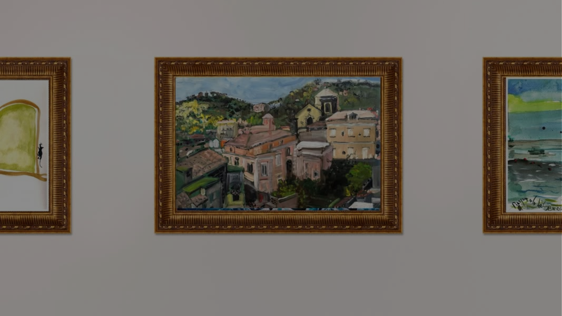 A wide view of a gallery wall featuring three framed paintings: a whimsical cat illustration, a traditional oil painting of a local village, and a coastal watercolor.