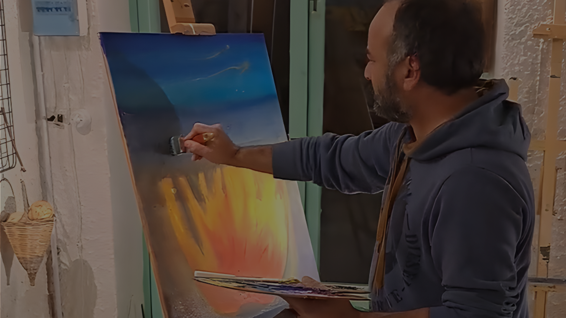 An artist painting a colorful canvas on an easel during a creative workshop at Under the Arch Art Gallery in Sant&rsquo;Agata.