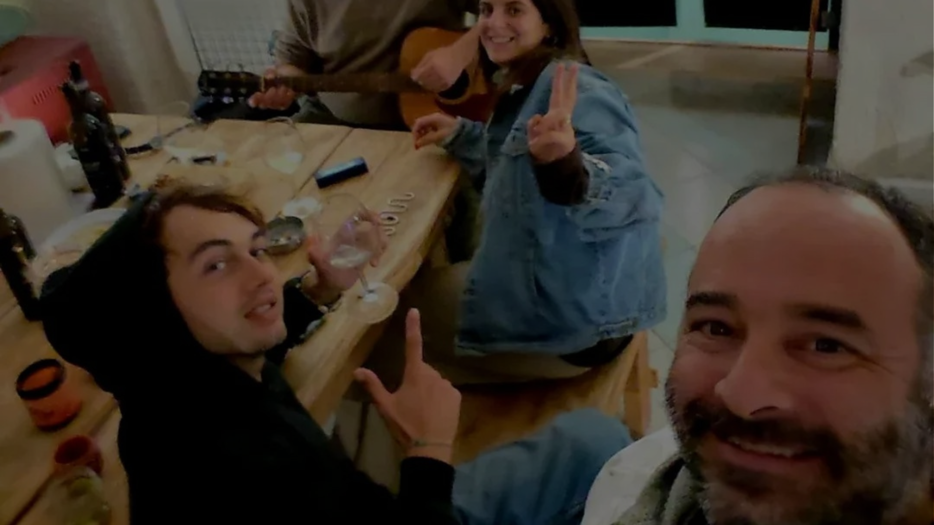 A group of people enjoying a social gathering at Under the Arch Art Gallery, with live guitar music, wine, and a friendly atmosphere.