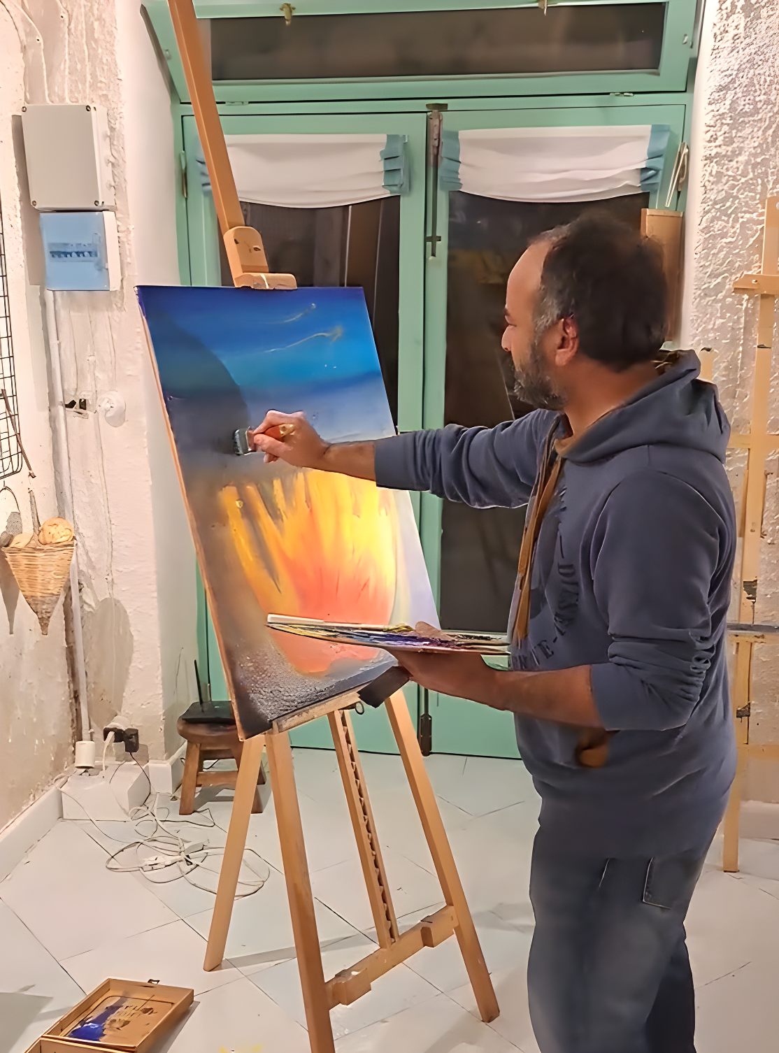 An artist painting a colorful canvas on an easel during a creative workshop at Under the Arch Art Gallery in Sant’Agata.