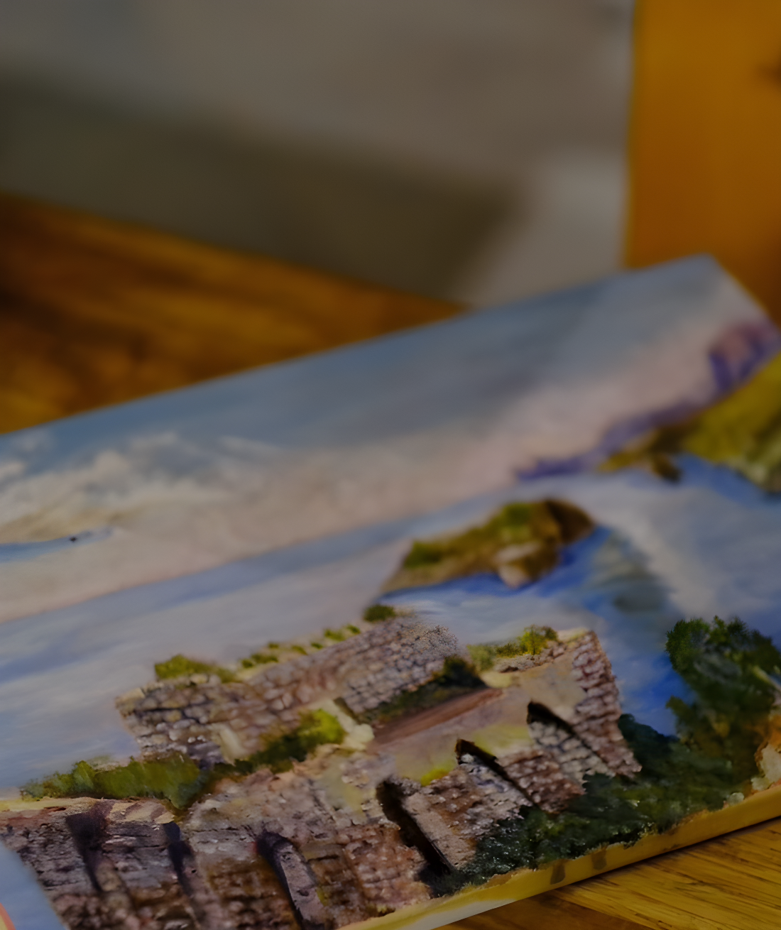 Close-up of a contemporary painting depicting a coastal Italian village with stone buildings and blue sea, created during a gallery workshop.