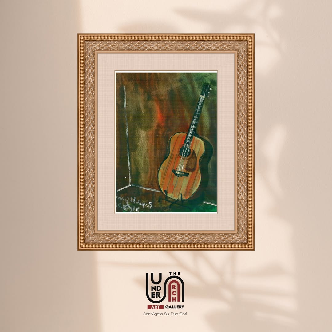 A framed watercolor painting of an acoustic guitar against a warm, textured background, displayed in an elegant gold frame.